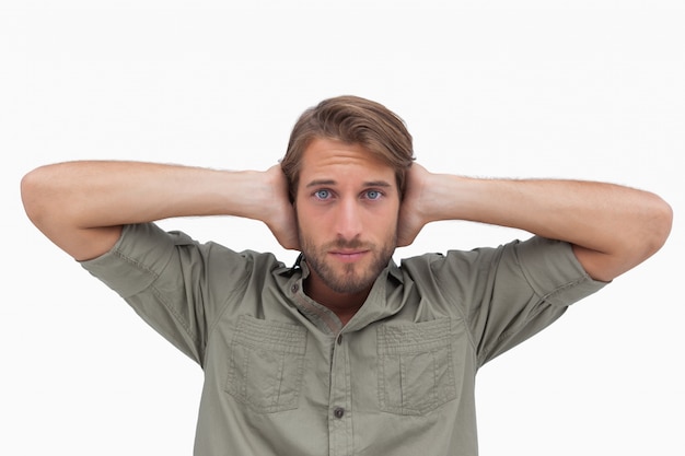 Homme bloquant ses oreilles et regardant la caméra