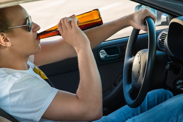 L'homme boit de la bière dans sa voiture