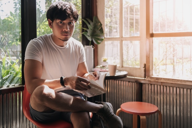 L'homme boit du café et un livre de lecture en été chaud et léger