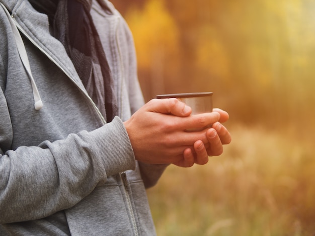 Un homme boit du thé chaud d'un thermos dans la nature en automne