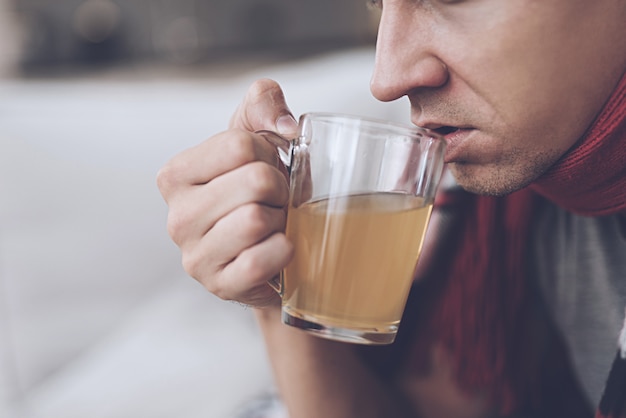 Un homme boit du thé à l&#39;orange dans une tasse en verre