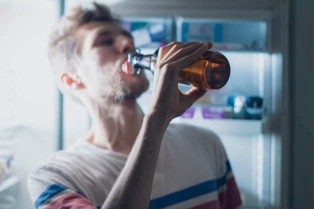 L'homme boit l'ours du réfrigérateur la nuit b