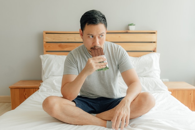 L&#39;homme boit une tasse de café sur le lit dans sa chambre.