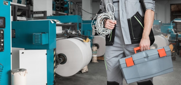 Homme avec boîte à outils travaillant dans une imprimerie avec une machine à imprimer