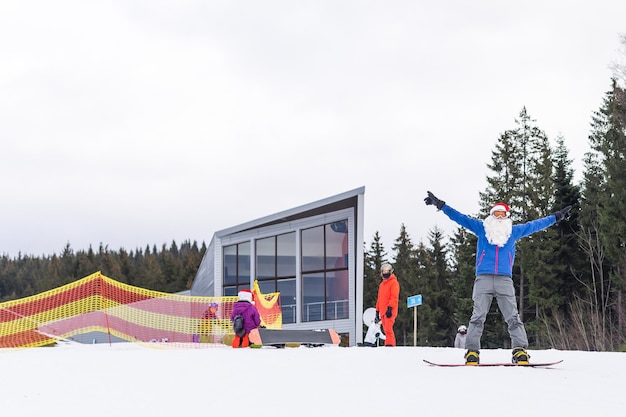 un homme en bonnet de noel avec un snowboard dans une station de ski.