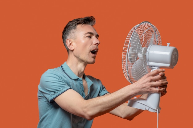 Homme avec la bouche ouverte devant le ventilateur