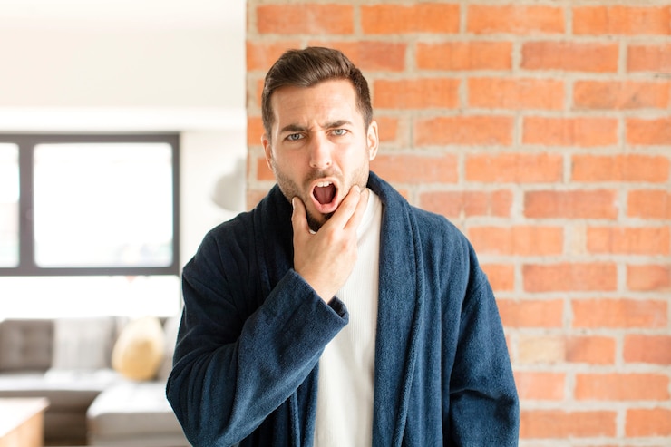 Photo homme avec la bouche et les yeux grands ouverts et la main sur le menton, se sentant désagréablement choqué, disant quoi ou wow