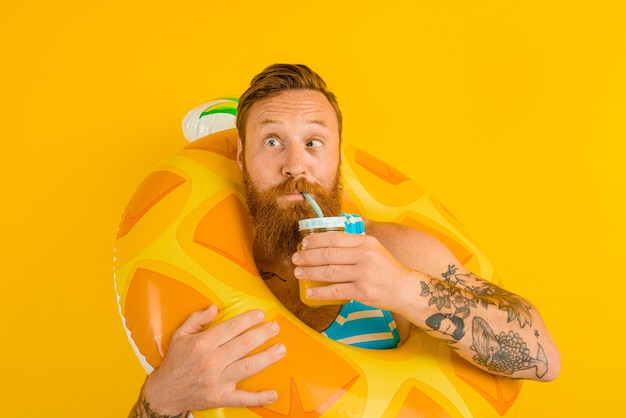 L'homme avec la bouée de sauvetage de l'enfant boit un jus de fruit