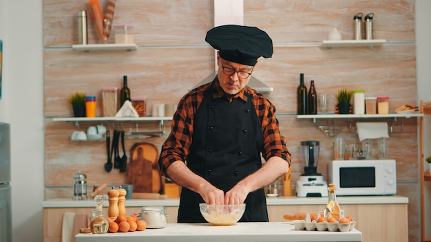 Homme boulanger utilisant de la farine pour une recette traditionnelle savoureuse dans la cuisine à domicile parlant à la caméra. Chef influenceur blogueur à la retraite utilisant la technologie Internet communiquant sur les médias sociaux avec un équipement numérique