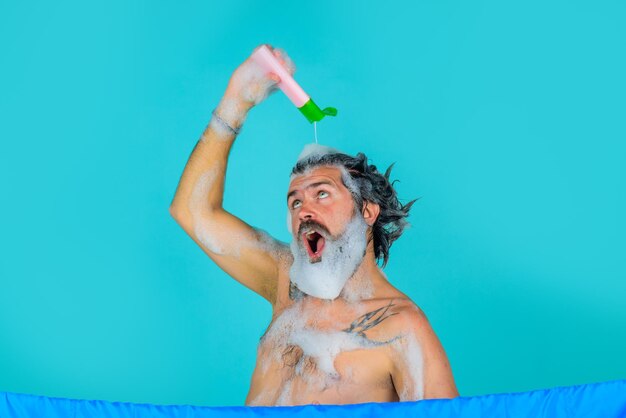 Homme avec une bouteille de shampoing Homme dans une douche Homme avec de la mousse sur la tête Bouteille de shampoing lave-tête homme barbu