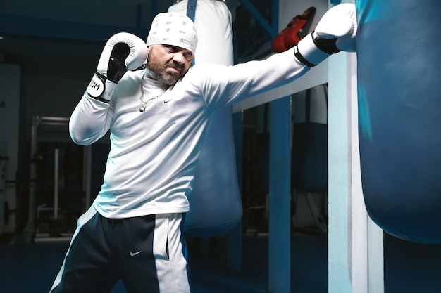 Homme boxeur avec des gants blancs dans la salle de gym