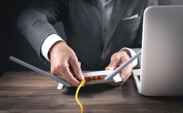 Homme branchant le câble Internet au routeur wifi.