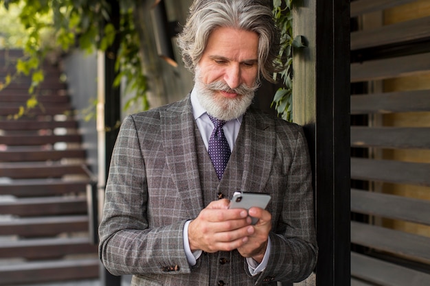 Homme branché avec barbe, navigation sur téléphone mobile