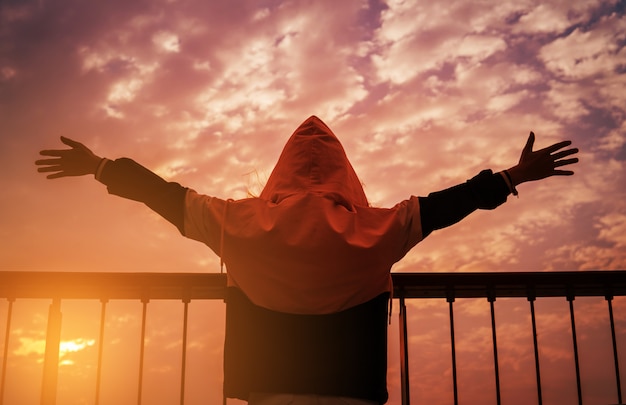 Homme à bras ouverts au coucher du soleil