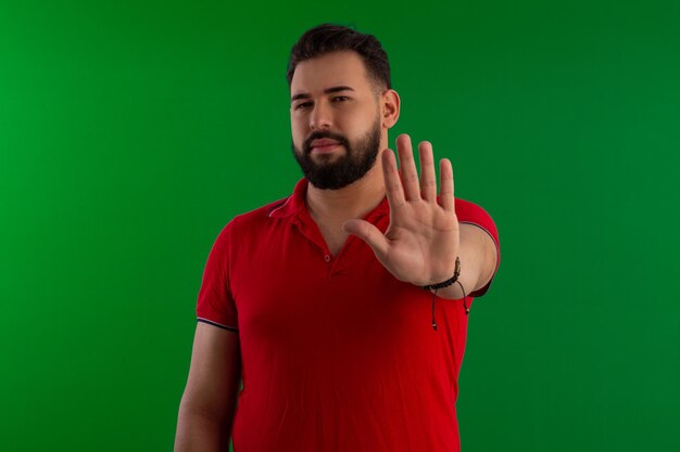 Homme brésilien avec une barbe portant une chemise rouge dans un studio photo avec un fond vert idéal pour le recadrage
