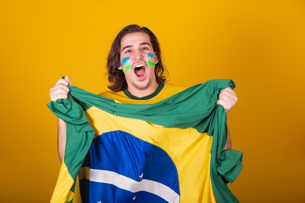 Homme brésilien Caucasien latino-américain acclamant le Brésil lors de la coupe du monde 2022 Patriote nationaliste Drapeau du Brésil vibrant acclamant et sautant symbole de bonheur joie et de célébration avec le drapeau du Brésil