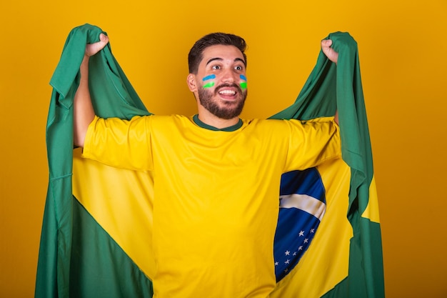 Homme brésilien latino-américain acclamant le brésil lors de la coupe du monde 2022 Nationaliste patriote Drapeau du brésil vibrant acclamant et sautant symbole de bonheur joie et de célébration avec le drapeau du brésil