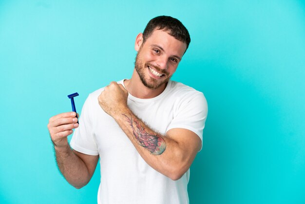 Homme brésilien rasant sa barbe isolé sur fond bleu célébrant une victoire