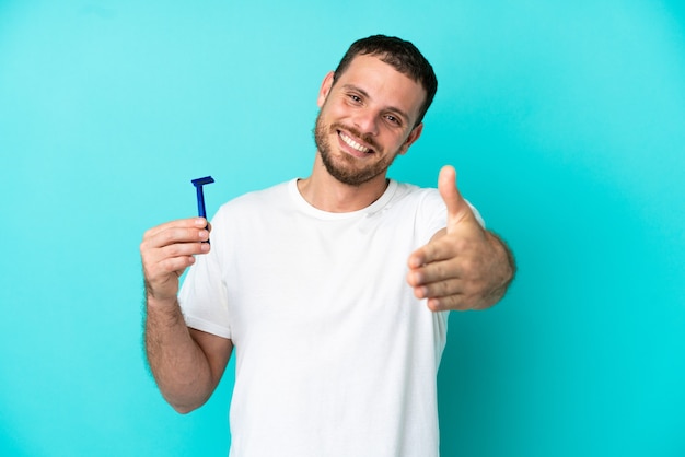 Homme brésilien rasant sa barbe isolé sur fond bleu se serrant la main pour conclure une bonne affaire