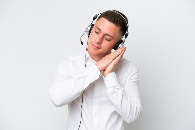 Homme brésilien de télévendeur travaillant avec un casque isolé sur fond blanc faisant un geste de sommeil dans une expression dorable