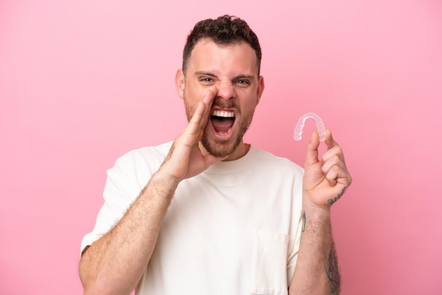 Homme brésilien tenant des bretelles invisibles criant avec la bouche grande ouverte