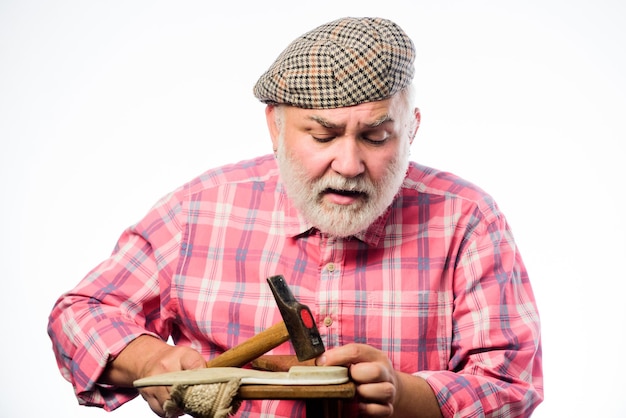 Homme bricoleur barbu travaillant avec des outils fond blanc Chaussures sur mesure Atelier de réparation de chaussures Maître principal avec un marteau réparant une chaussure Concept fait à la main Conception de chaussures Ouvrier artisan