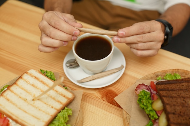 Homme brise le sucre avant de le verser dans une tasse à café