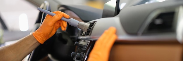 Un homme brosse la poussière à l'intérieur d'un plan rapproché de mains de voiture