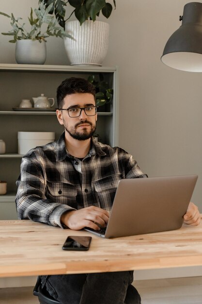 Un homme brune à lunettes travaille à la maison devant l'ordinateur