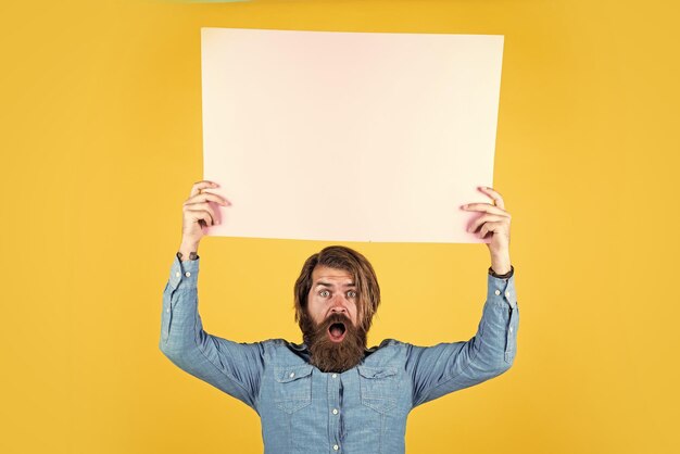 Un homme brutal barbu étonné avec une moustache tient de la merde de papier pour la publicité de l'espace de copie