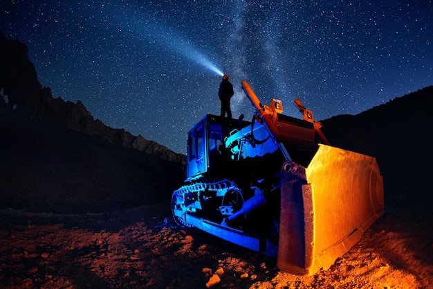 Homme sur bulldozer avec ciel nocturne