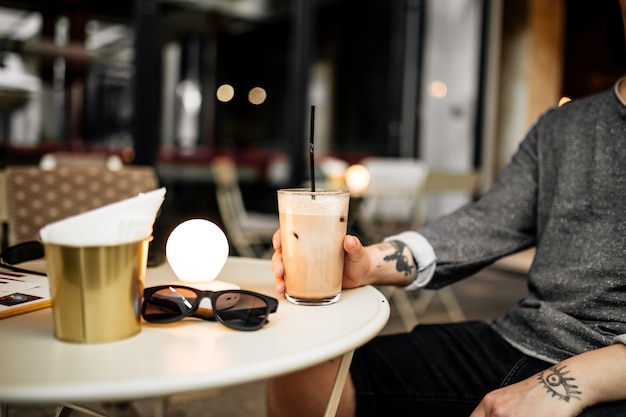 Homme buvant du café latte assis sur la terrasse d'été au café