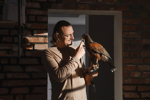 Homme buvant du café avec un oiseau sauvage à la maison dans une cuisine ensoleillée