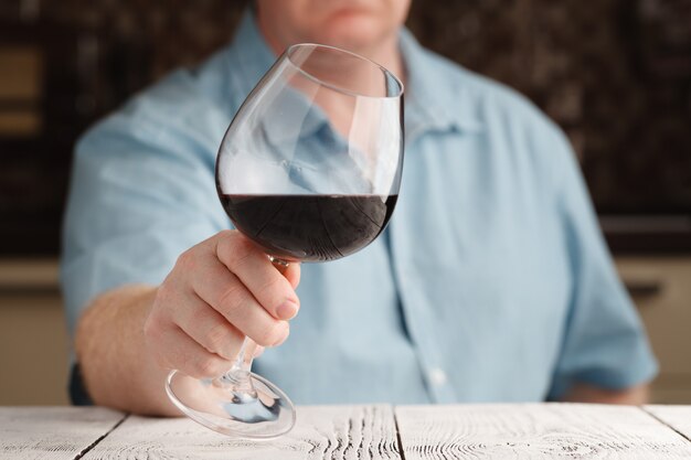 Homme buvant du vin rouge dans la cuisine