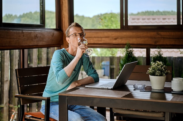 Homme buvant du vin tout en discutant dans Messenger sur ordinateur portable