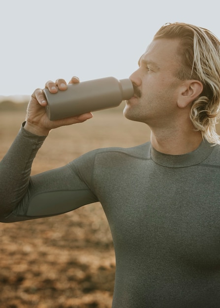 Homme buvant de l'eau à partir d'une bouteille en acier inoxydable après avoir fait de l'exercice