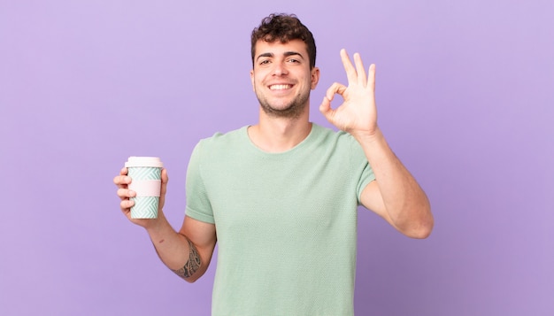 Homme avec café se sentant heureux, détendu et satisfait, montrant son approbation avec un geste correct, souriant