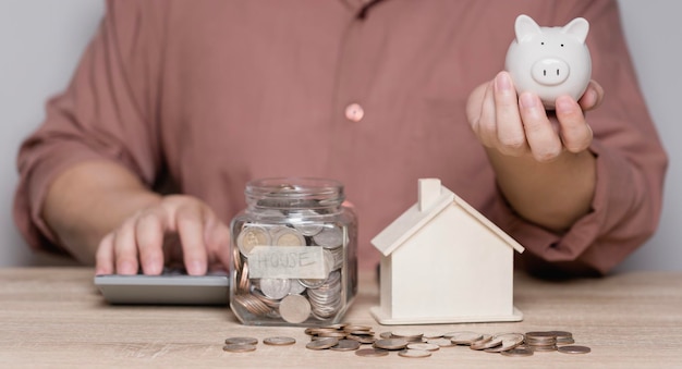 Un homme calcule de l'argent pour économiser et le met dans une tirelire Idées pour économiser de l'argent pour de futurs achats de maison et l'utiliser à l'avenir après la retraite Dépenses familiales