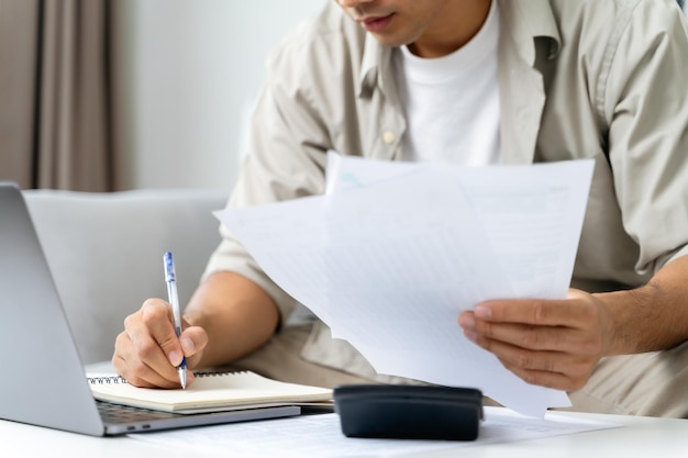 Photo l'homme calcule l'impôt annuel avec une calculatrice et remplit le formulaire de déclaration d'impôt sur le revenu individuel