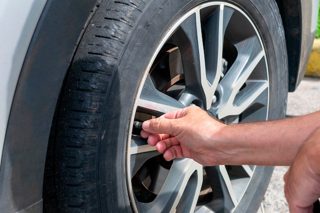 Homme calibrant un pneu de voiture