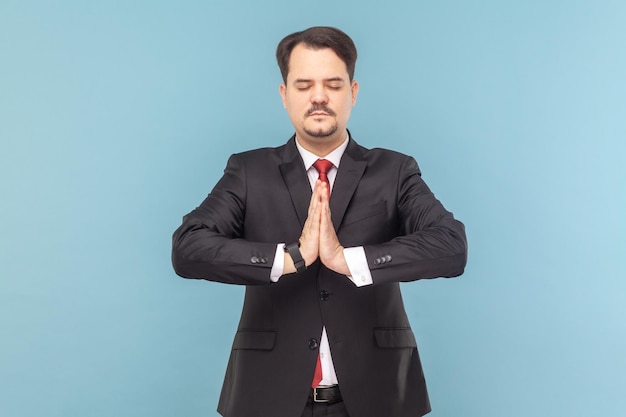 Homme calme avec moustache debout avec fermé pratiquant le yoga méditant tout en ayant une pause au travail