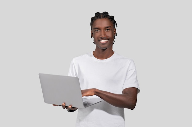 Un homme calme avec un ordinateur portable souriant à la caméra.