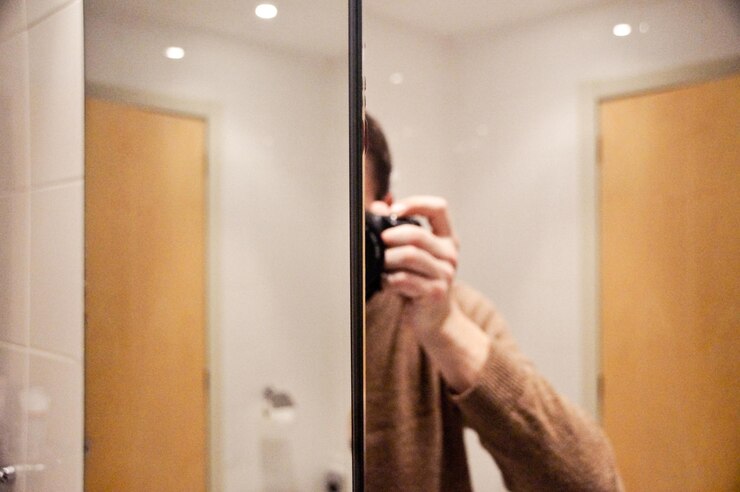 Photo un homme avec une caméra réfléchissant sur le miroir de la salle de bain