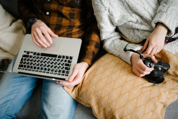 L'homme sur le canapé travaille sur un ordinateur portable, la femme est assise à côté