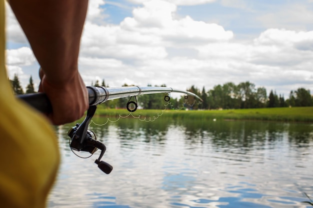 Un homme avec une canne à pêche sur la rive du fleuve pêche