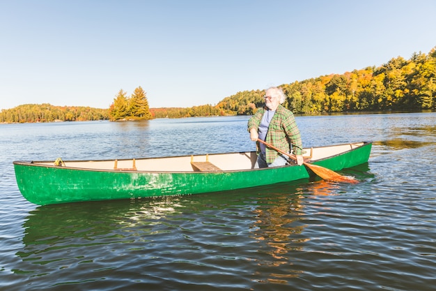 Homme avec canoë au lac un jour d&#39;automne ensoleillé