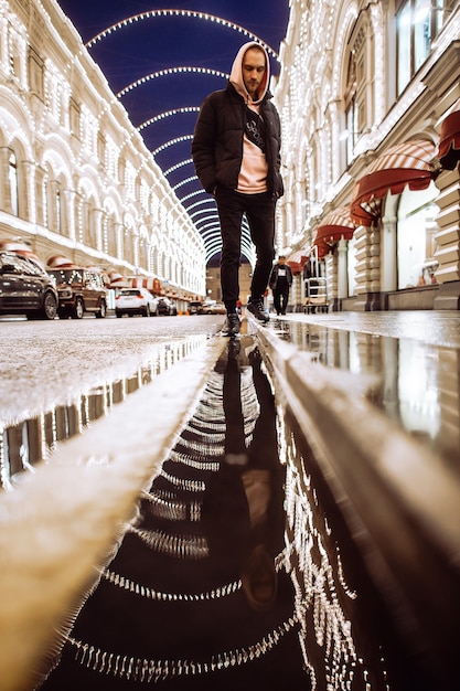 Homme à capuche la nuit dans la rue pluvieuse.