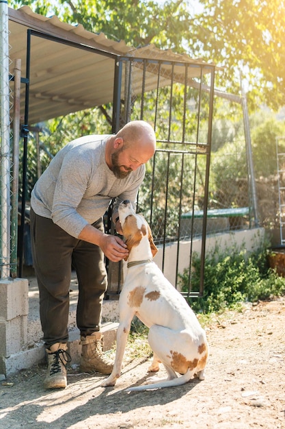 Homme caressant un chien dans la cour d'une maison