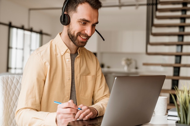 Homme avec casque ayant un appel vidéo sur ordinateur portable