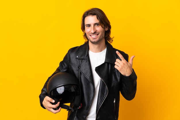 Homme avec un casque de moto isolé sur jaune donnant un geste de pouce en l'air